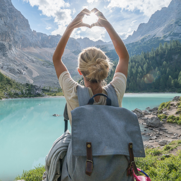 Woman near lake making heart symbol