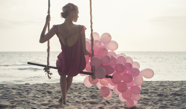 woman with balloons on beach
